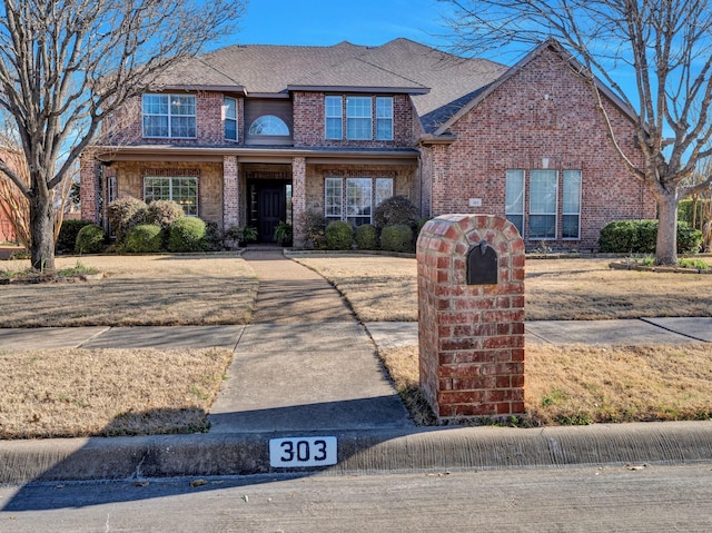 view of front of home featuring a shingled roof and brick siding