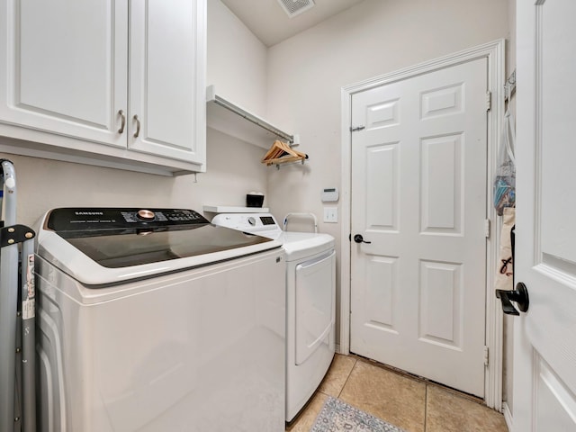 laundry area with light tile patterned floors, cabinet space, visible vents, and separate washer and dryer