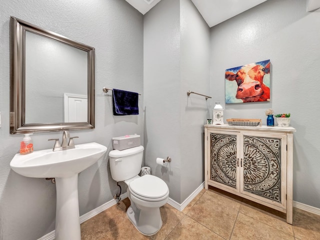 bathroom with toilet, baseboards, a sink, and tile patterned floors