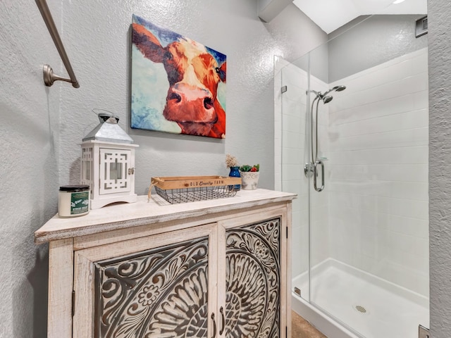 bathroom with a textured wall, a shower stall, and vanity