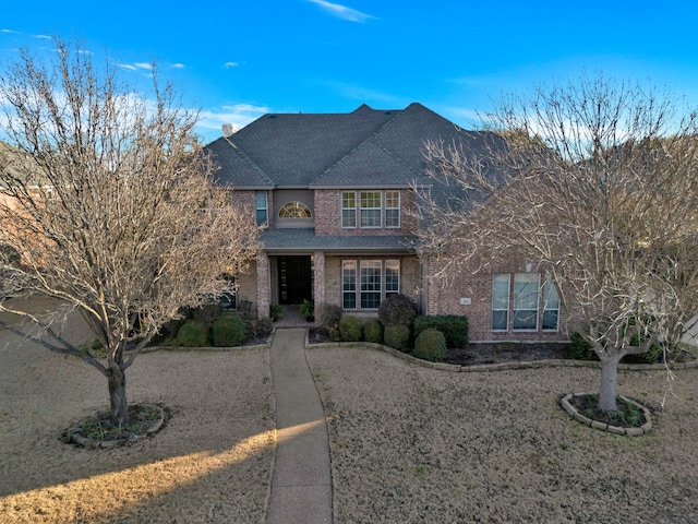 traditional home featuring brick siding and roof with shingles