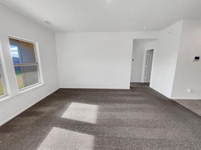 spare room with carpet, visible vents, and baseboards