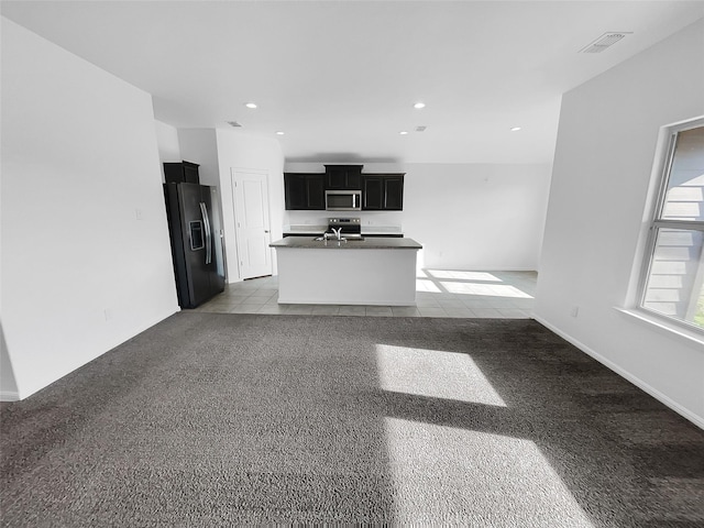 kitchen featuring light colored carpet, dark cabinets, stainless steel appliances, visible vents, and dark countertops