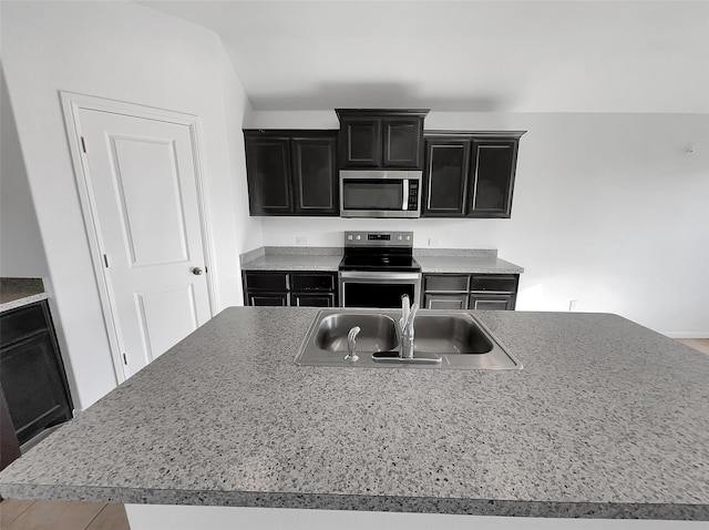 kitchen featuring a sink, appliances with stainless steel finishes, light countertops, and dark cabinetry