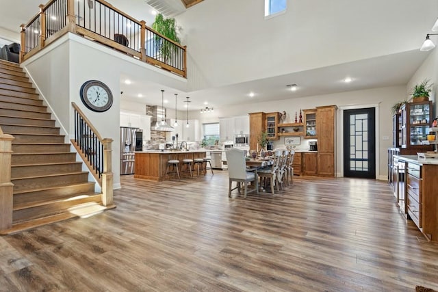 dining room featuring dark wood finished floors, recessed lighting, a towering ceiling, baseboards, and stairs