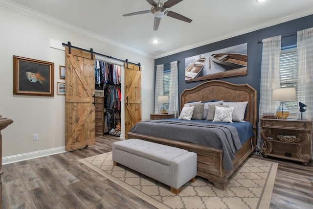 bedroom featuring ornamental molding, a barn door, and wood finished floors