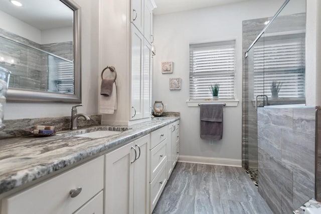 full bathroom with a stall shower, vanity, and baseboards