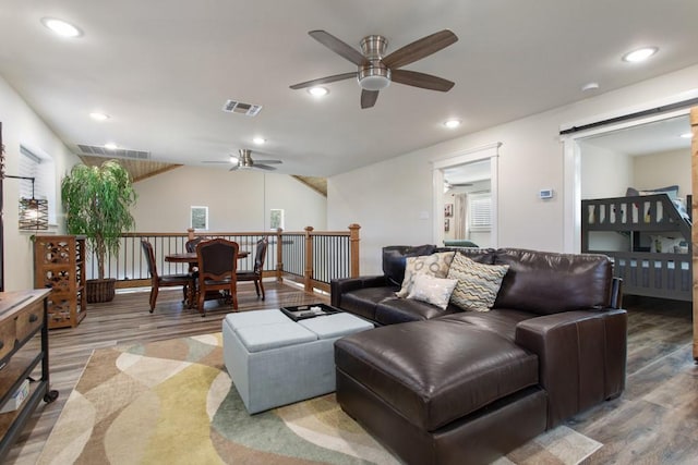 living area featuring wood finished floors, visible vents, and a barn door