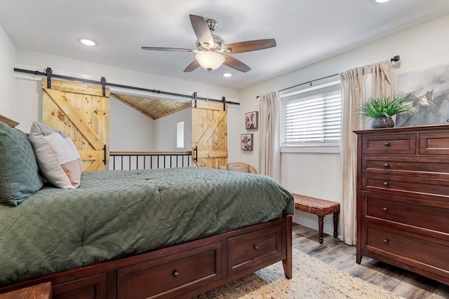 bedroom with a ceiling fan, recessed lighting, light wood finished floors, and a barn door