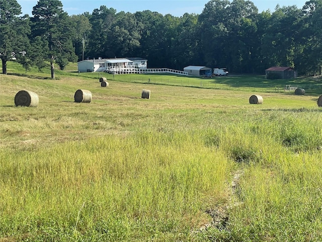 view of yard with a rural view, fence, and a forest view