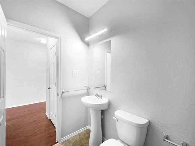 bathroom with baseboards, a sink, toilet, and wood finished floors