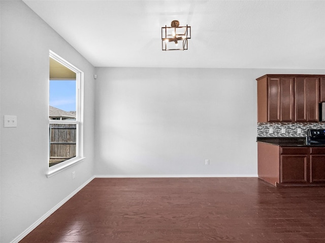 unfurnished dining area with dark wood-style floors and baseboards