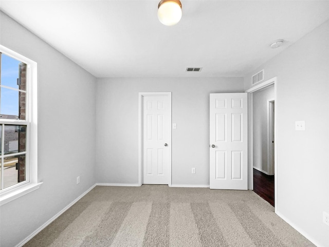 unfurnished bedroom with carpet, visible vents, and baseboards