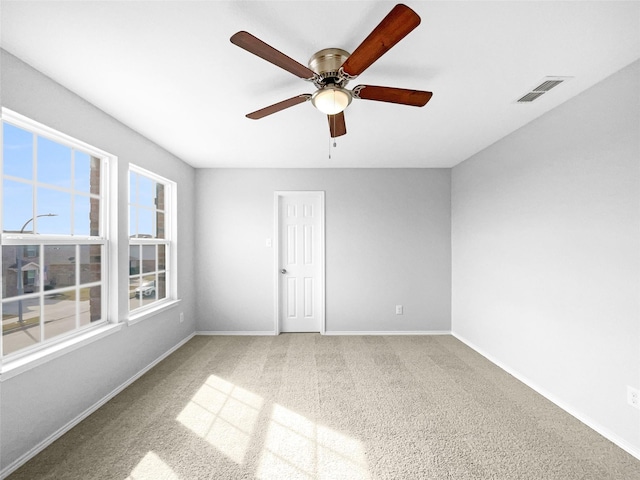 spare room featuring carpet floors, a ceiling fan, visible vents, and baseboards