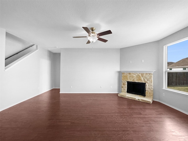 unfurnished living room with dark wood-type flooring, a fireplace, a textured ceiling, and ceiling fan