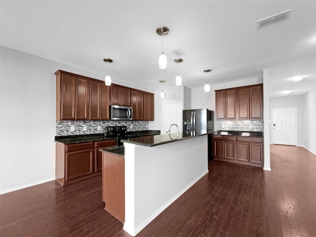 kitchen with dark countertops, dark wood-style floors, visible vents, and appliances with stainless steel finishes