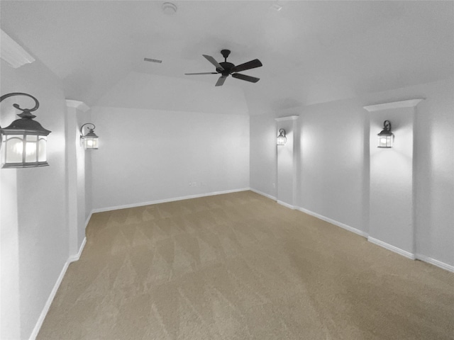 unfurnished room with carpet floors, visible vents, a ceiling fan, vaulted ceiling, and baseboards