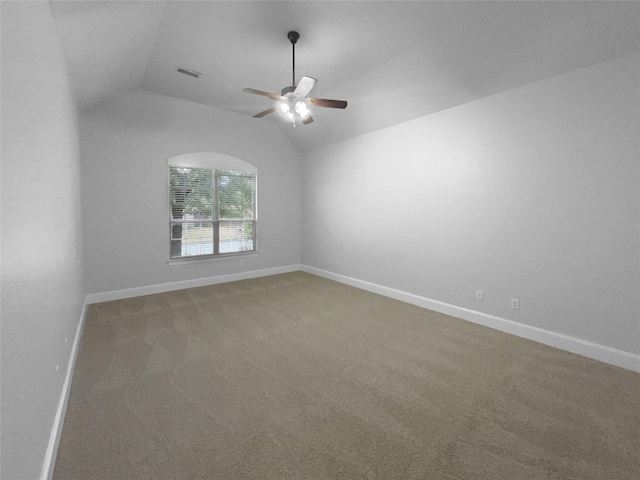 carpeted spare room with lofted ceiling, baseboards, visible vents, and ceiling fan