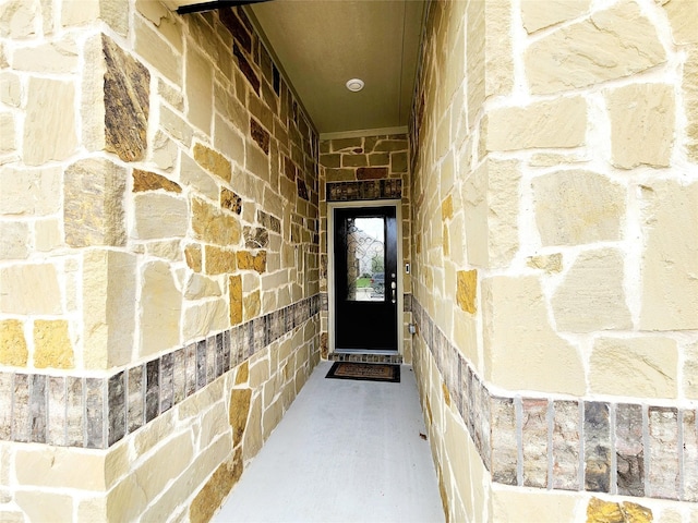 view of exterior entry featuring stone siding and brick siding