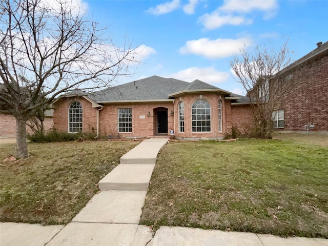 ranch-style house featuring brick siding, roof with shingles, and a front yard