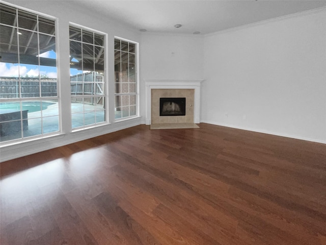 unfurnished living room with a tile fireplace, baseboards, and wood finished floors