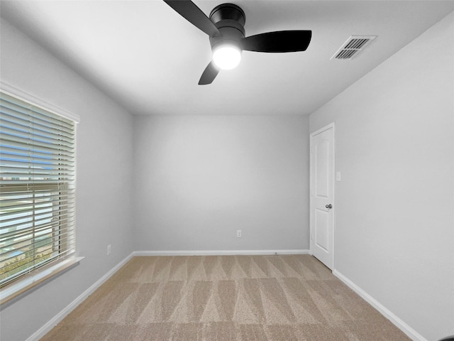 empty room with baseboards, ceiling fan, visible vents, and light colored carpet