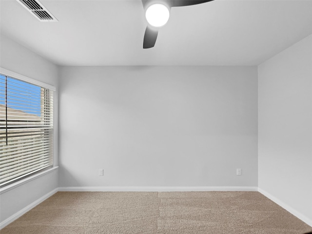 carpeted spare room featuring a ceiling fan, visible vents, and baseboards