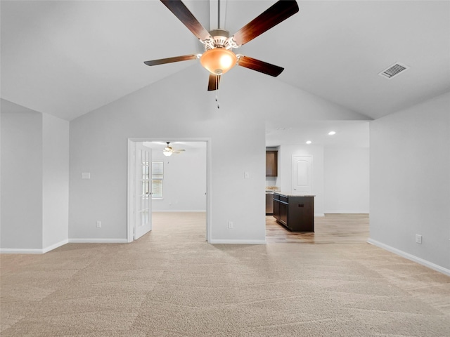 unfurnished living room with baseboards, high vaulted ceiling, visible vents, and light colored carpet