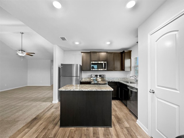 kitchen featuring a kitchen island, a sink, visible vents, appliances with stainless steel finishes, and light stone countertops