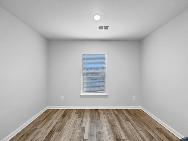 unfurnished room with wood finished floors, visible vents, and baseboards