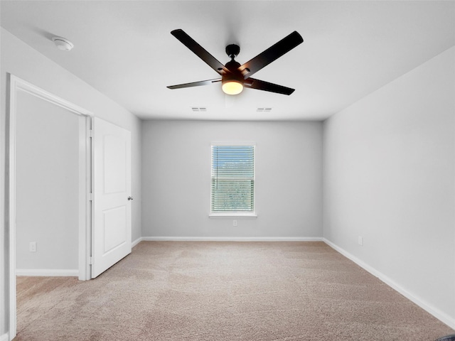 carpeted spare room featuring visible vents, baseboards, and a ceiling fan