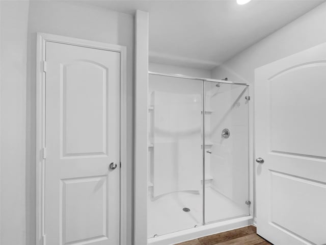 bathroom with a stall shower and wood finished floors