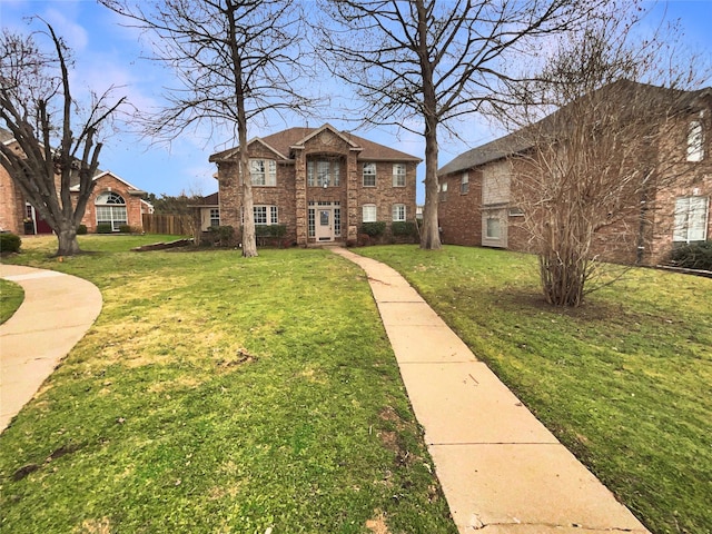 view of front facade with brick siding and a front lawn