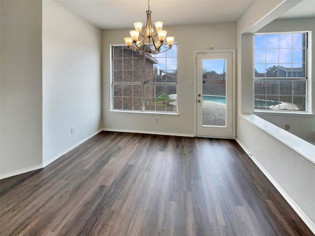 unfurnished dining area featuring a notable chandelier, baseboards, and wood finished floors