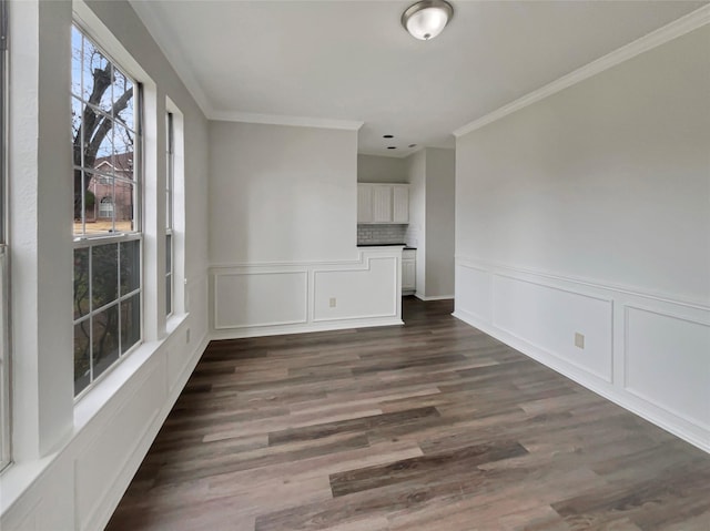 spare room featuring dark wood finished floors, crown molding, and a decorative wall