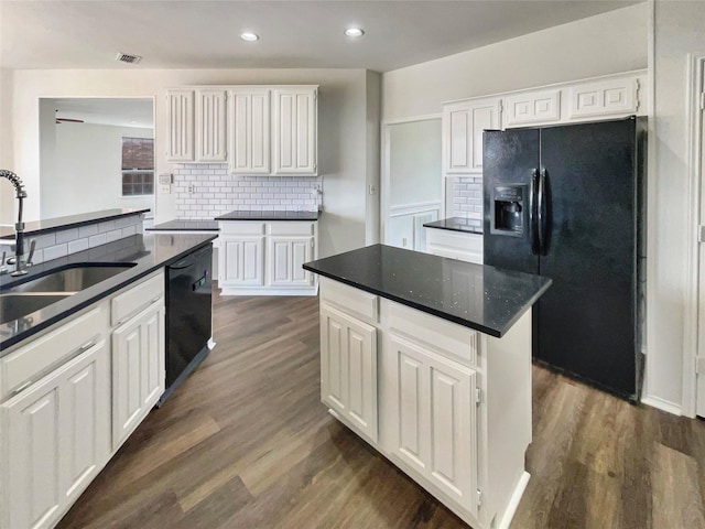 kitchen featuring dark wood-style floors, dark countertops, a sink, and black appliances