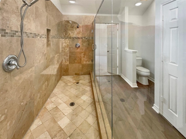 bathroom with toilet, a shower stall, and baseboards