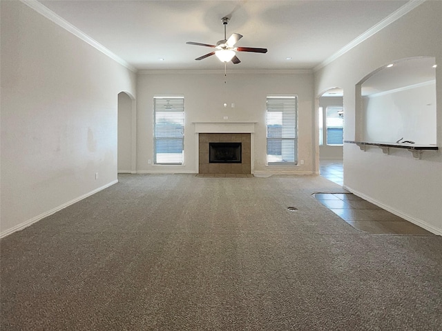 unfurnished living room with carpet floors, plenty of natural light, crown molding, and a tiled fireplace