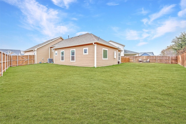 rear view of property featuring a fenced backyard, central AC unit, and a yard