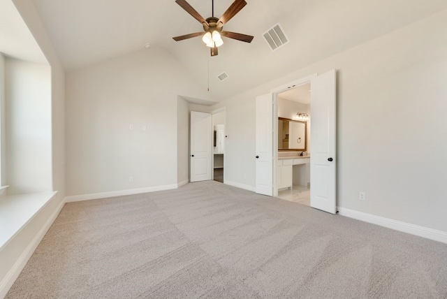 unfurnished bedroom featuring baseboards, visible vents, connected bathroom, light colored carpet, and lofted ceiling