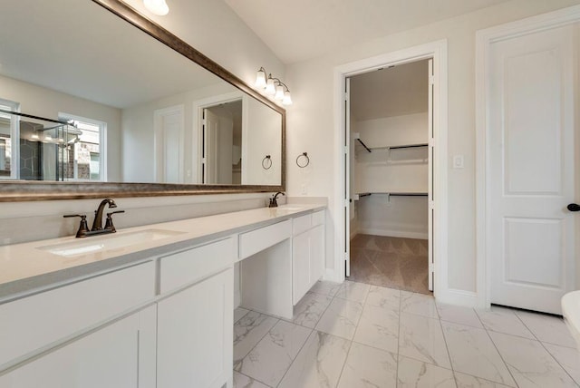 bathroom featuring double vanity, marble finish floor, a spacious closet, and a sink