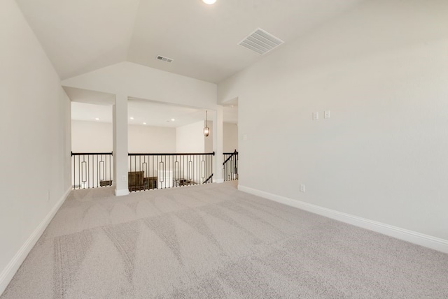 spare room with carpet, visible vents, vaulted ceiling, and baseboards