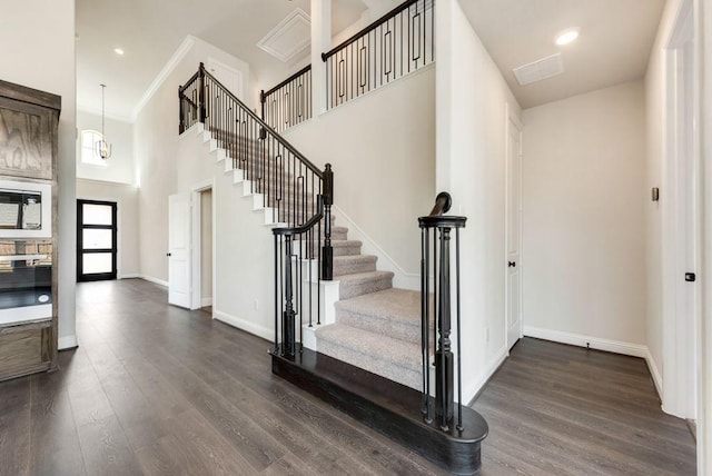 stairway featuring recessed lighting, visible vents, a high ceiling, wood finished floors, and baseboards