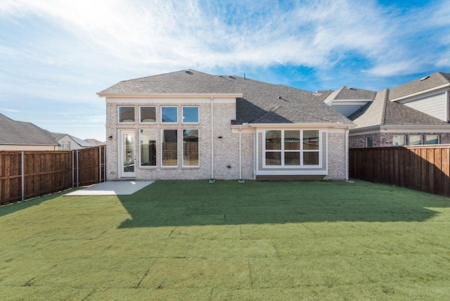 back of property with brick siding, a yard, and a fenced backyard