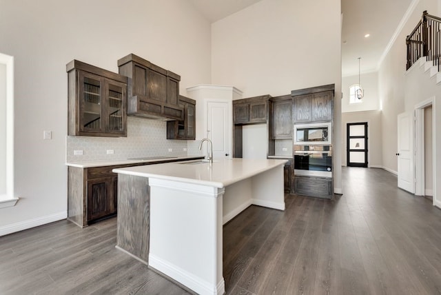 kitchen with dark brown cabinetry, dark wood-type flooring, stainless steel appliances, and a sink