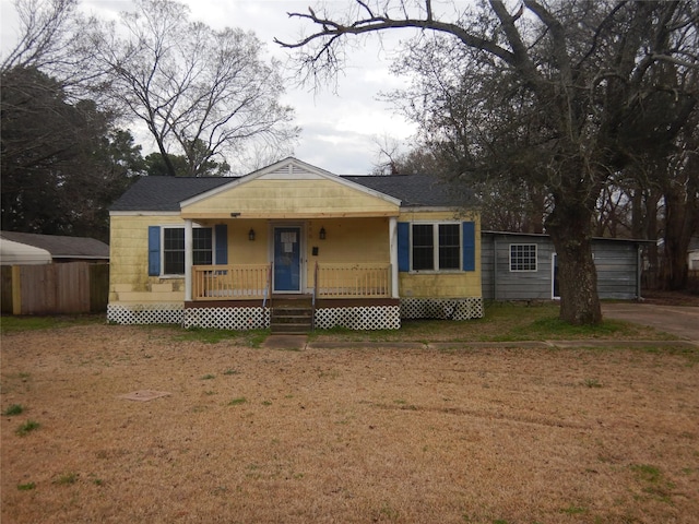 bungalow-style house with a porch, a front yard, and roof with shingles