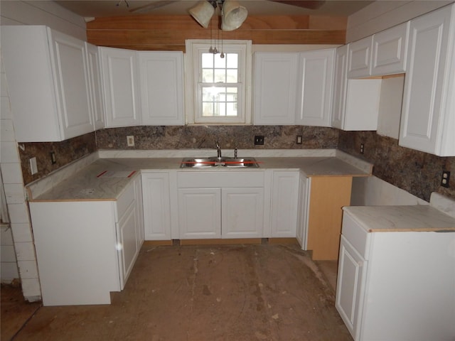 kitchen with decorative backsplash, ceiling fan, hanging light fixtures, white cabinetry, and a sink