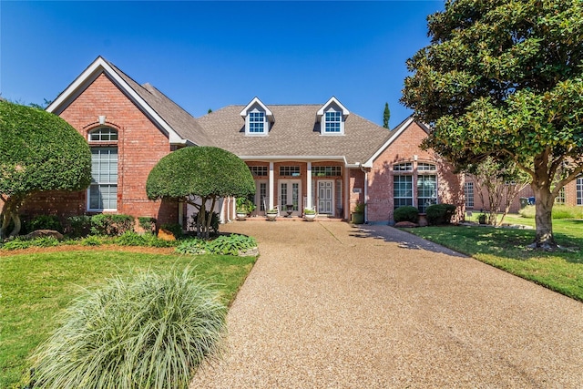 view of front facade featuring french doors, brick siding, and a front lawn