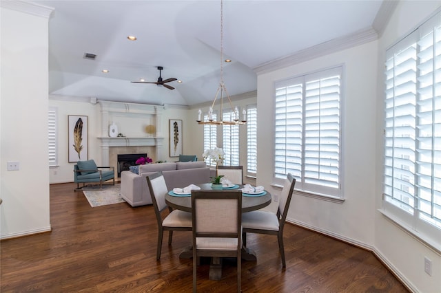 dining space featuring a fireplace, crown molding, lofted ceiling, visible vents, and dark wood-type flooring