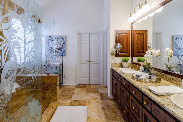 full bath featuring double vanity, a sink, a high ceiling, and a walk in shower